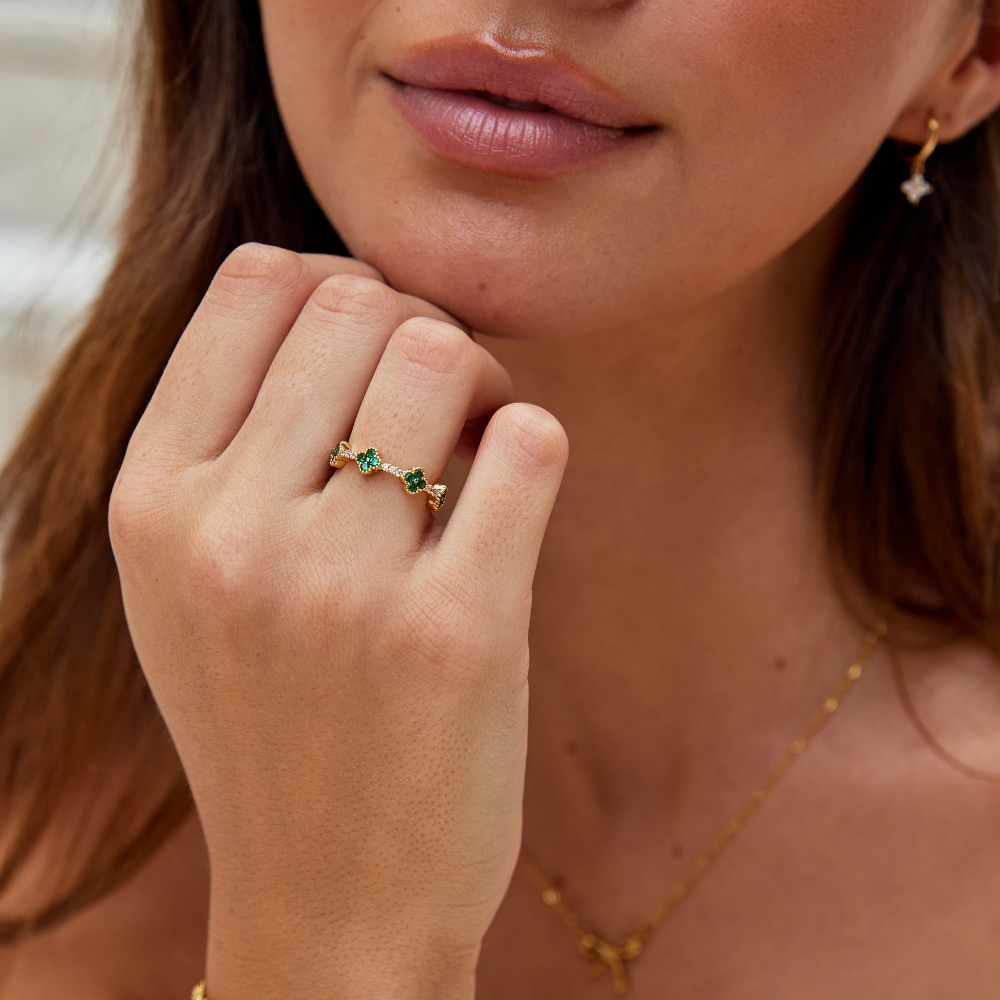 Annika – Guld ring med blommiga detaljer och smaragdinslag.
